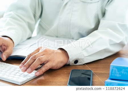 一名穿著工作服的男子正在操作電腦 118872624