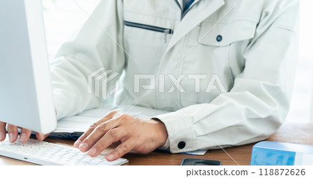 一名穿著工作服的男子正在操作電腦 一名穿著工作服的男子正在操作電腦 118872626