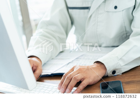 A man in work clothes operating a computer 118872632