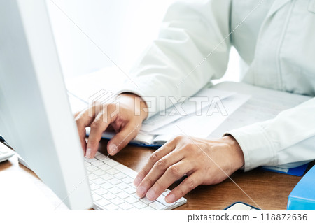 A man in work clothes operating a computer A man in work clothes operating a computer 118872636