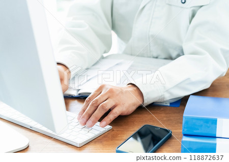 A man in work clothes operating a computer 118872637