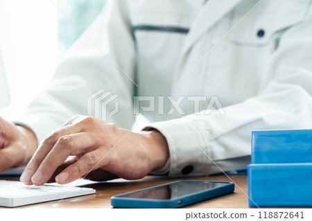 A man in work clothes operating a computer A man in work clothes operating a computer 118872641