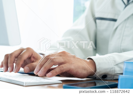A man in work clothes operating a computer 118872642