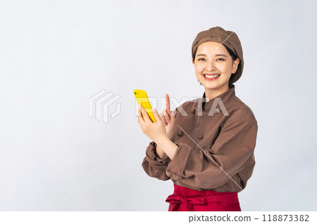 A woman in a cooking uniform using a smartphone, a chef, a restaurant employee A woman in a cooking uniform using a smartphone, a chef, a restaurant employee 118873382