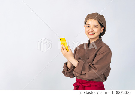 A woman in a cooking uniform using a smartphone, a chef, a restaurant employee 118873383