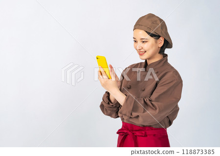 A woman in a cooking uniform using a smartphone, a chef, a restaurant employee A woman in a cooking uniform using a smartphone, a chef, a restaurant employee 118873385
