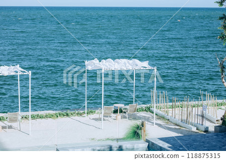 A serene seaside retreat with two wooden chairs. 118875315
