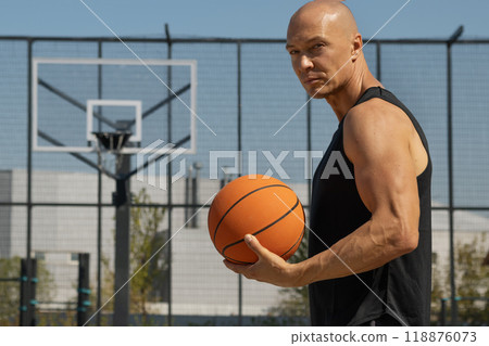 Basketball player hold orange basketball ball on sports field. Outdoors game. Basketball coach. Summer. 118876073