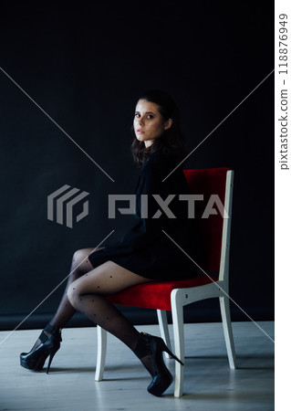 Beautiful fashionable brunette woman sitting on a red chair 118876949