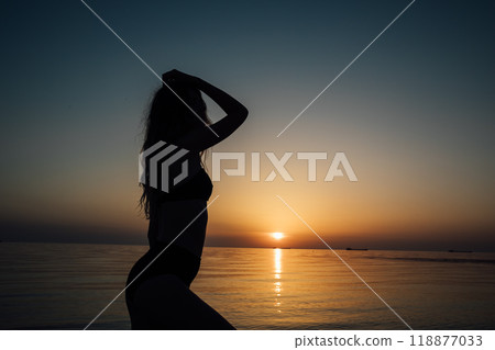 Silhouette of slender woman in sea water at sunset 118877033
