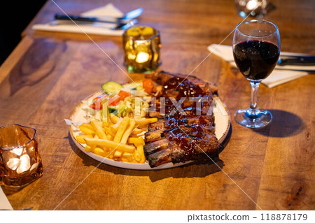Tender grilled porterhouse or t-bone steak served with crisp golden French fries and fresh green herb salad accompanied by a BBQ or tomato ketchup sauce 118878179