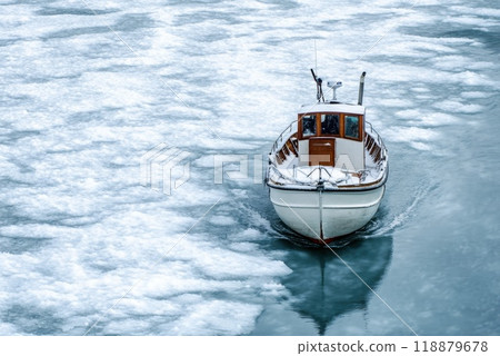 A boat navigating through frozen waters in a serene winter landscape 118879678