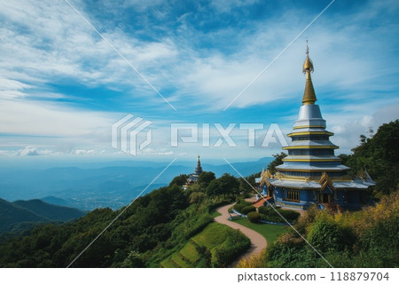 Mountaintop temple with golden spires surrounded by lush greenery in a serene landscape during daylight 118879704