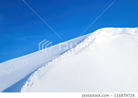 Snow covered mountain peak against a clear blue sky during daylight with soft snow texture enhancing the serene landscape Snow covered mountain peak against a clear blue sky during daylight with soft snow texture enhancing the serene landscape 118879726