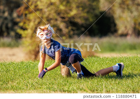 Cute young little kid girl wear cat furry mask enjoy have fun playing outdoors in forest street park. Children therian wild animal character trendy fan culture. Teenager social expression hobby Cute young little kid girl wear cat furry mask enjoy have fun playing outdoors in forest street park. Children therian wild animal character trendy fan culture. Teenager social expression hobby 118880471