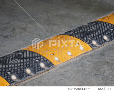 yellow and black traffic safety speed bump on a concrete road at parking lot. High quality photo yellow and black traffic safety speed bump on a concrete road at parking lot. High quality photo 118881077