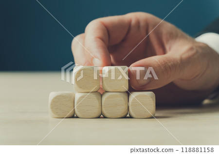 Businessman placing two blank wooden dices on top of four others Businessman placing two blank wooden dices on top of four others 118881158