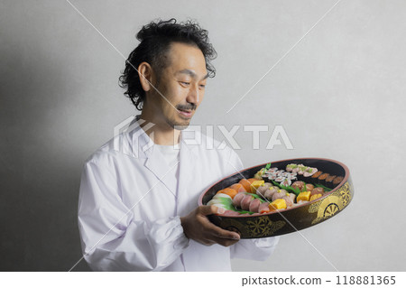 A man in a white coat holding a sushi tub 118881365