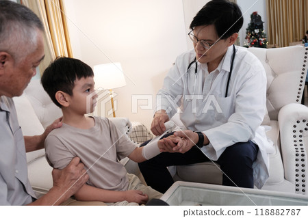 The doctor treats a wound on a boy's arm. 118882787