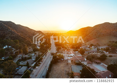 This is an aerial view portraying a city alongside a highway at sunset 118882915