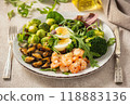 Shrimp and mussels cooked in coconut oil, served with greens, brussels sprouts, broccoli and eggs. Keto diet. 118883136