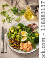 Shrimp and mussels cooked in coconut oil, served with greens, brussels sprouts, broccoli and eggs. Keto diet. 118883137