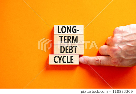 Long-term debt cycle symbol. Concept words Long-term debt cycle on beautiful wooden block. Beautiful orange table orange background. Businessman hand. Business Long-term debt cycle concept. Copy space 118883309