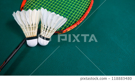 White badminton shuttlecocks and badminton rackets on green floor indoor badminton court. Concept for badminton competition and its lovers. White badminton shuttlecocks and badminton rackets on green floor indoor badminton court. Concept for badminton competition and its lovers. 118883480