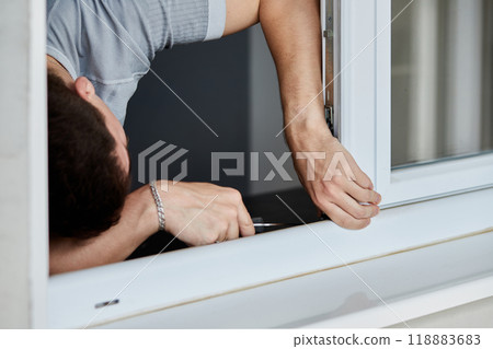 Young man repairing window with screwdriver at home. 118883683