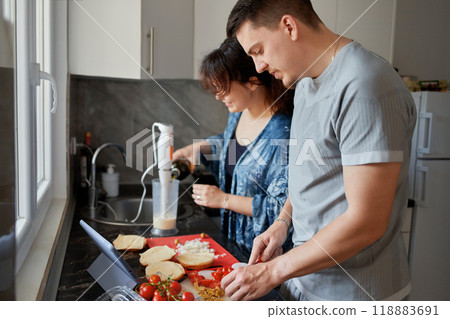 A young couple cooks food together at home using a tablet. A young couple cooks food together at home using a tablet. 118883691