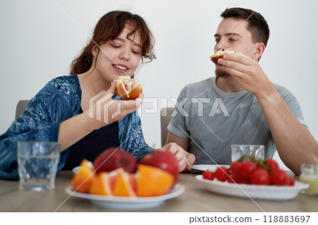 A young couple enjoys vegetarian sandwiches at home. A young couple enjoys vegetarian sandwiches at home. 118883697
