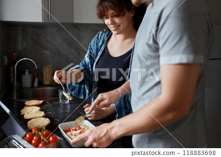 A young couple cooks food together at home using a tablet. 118883698