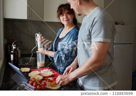 A young couple cooks food together at home using a tablet. A young couple cooks food together at home using a tablet. 118883699
