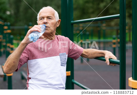 Old man drinking water in outdoor workout station 118883712