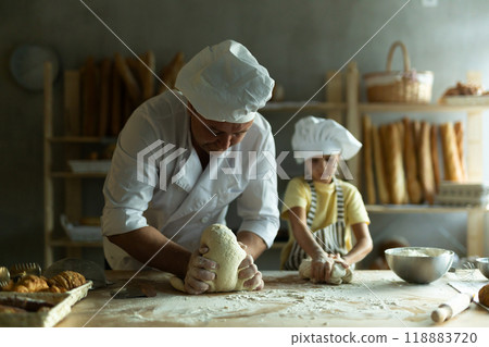 Daughter and father make dough together in the bakery kitchen Daughter and father make dough together in the bakery kitchen 118883720
