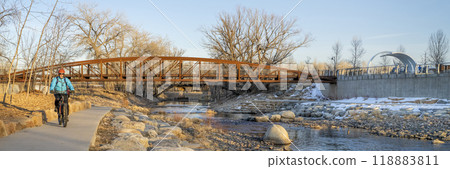male cyclist is riding a bike in winter sunset scenery - Poudre River Trail in Fort Collins, Colorado at downtown whitewater park, recreation and commuting concept male cyclist is riding a bike in winter sunset scenery - Poudre River Trail in Fort Collins, Colorado at downtown whitewater park, recreation and commuting concept 118883811