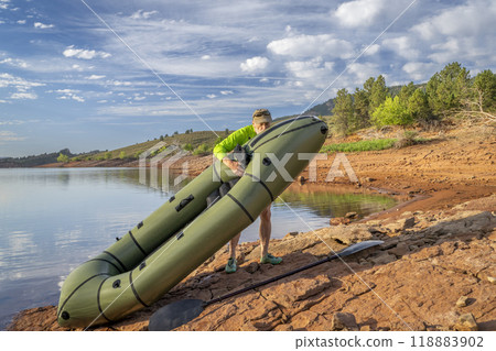 senior male paddler is adding air to an inflatable packraft on a lake shore in Colorado, summer on Horsetooth Reservoir senior male paddler is adding air to an inflatable packraft on a lake shore in Colorado, summer on Horsetooth Reservoir 118883902