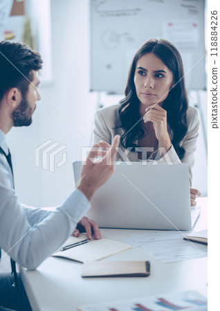 Important decisions every day. Two coworkers discussing something while sitting at the office table 118884226