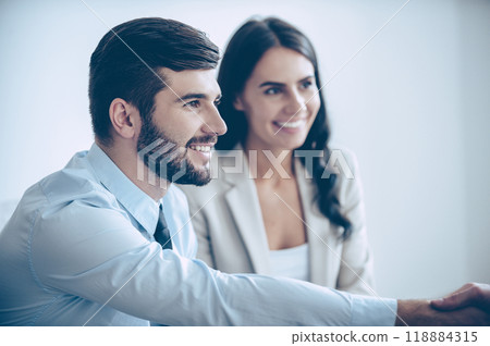 It is a pleasure to work with you! Close-up part of young handsome men shaking hands with smile while sitting at office with his coworkers 118884315