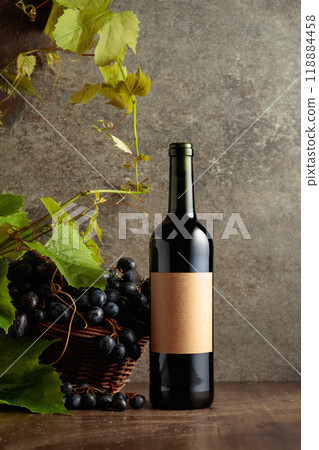 Bottle of red wine with blue grapes and vine branches. 118884458