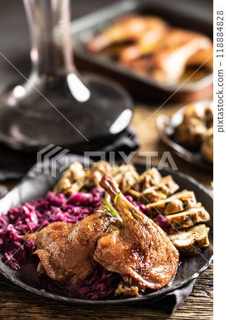 Portion of roast duck leg red cabbage homemade dumplings on plate and red wine on the background 118884828