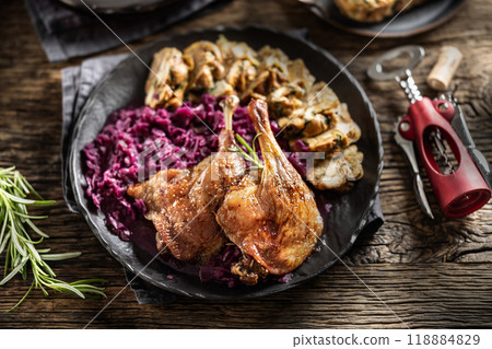 Portion of roast duck leg red cabbage homemade dumplings on plate and red wine on the background 118884829