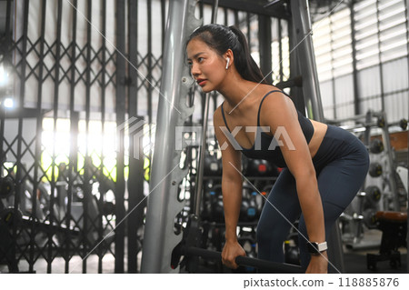Focused sporty Asian woman doing deadlift exercise at the gym, looking away with concentrated face Focused sporty Asian woman doing deadlift exercise at the gym, looking away with concentrated face 118885876
