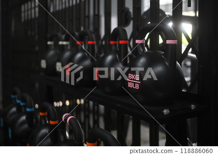 Sport equipments, a row of kettlebells are lined up on a shelf with the weights ranging Sport equipments, a row of kettlebells are lined up on a shelf with the weights ranging 118886060