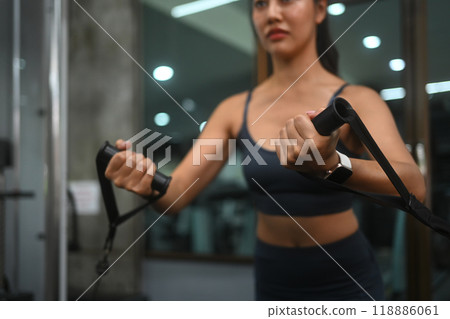 Young fit woman in sportswear lifting weights using a cable machine at the gym 118886061