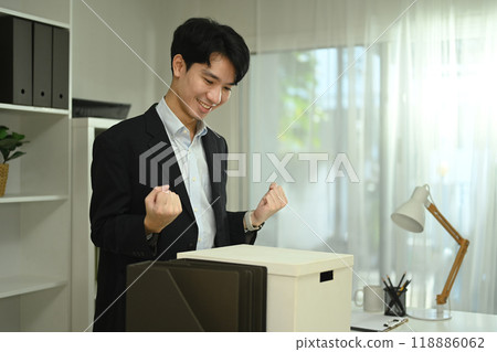 Happy asian male office worker with box of his belongings moving into a new office Happy asian male office worker with box of his belongings moving into a new office 118886062