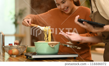 Cheerful young couple making delicious pasta in the kitchen Cheerful young couple making delicious pasta in the kitchen 118886072