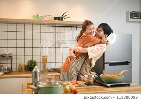 Affectionate young couple cooking healthy breakfast together and hugging in kitchen at home Affectionate young couple cooking healthy breakfast together and hugging in kitchen at home 118886089