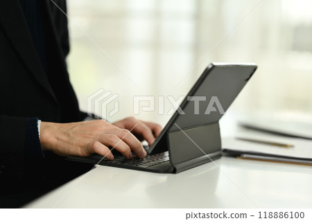 Close up shot of businessman typing on keyboard of digital tablet. Close up shot of businessman typing on keyboard of digital tablet. 118886100