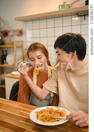 Happy young couple sharing a plate of spaghetti enjoying a casual meal in kitchen 118886185